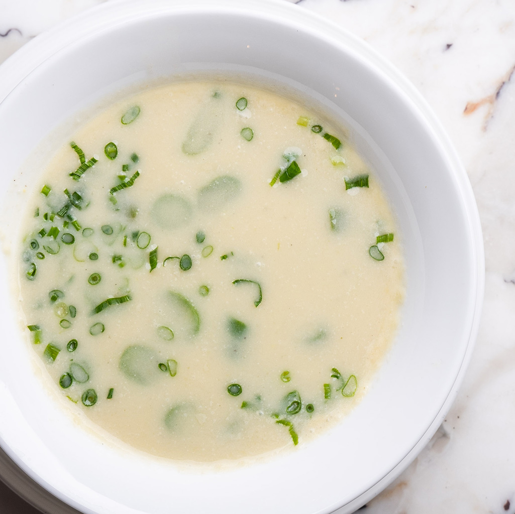 Cremige Spargelcremesuppe in weißer Schale, garniert mit frischem Schnittlauch (Serviervorschlag)