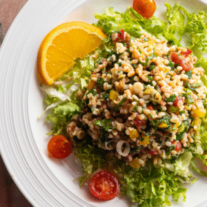 Bunter Bulgursalat mit Paprika, Petersilie und Frühlingszwiebeln auf grünem Salatbett (Serviervorschlag)