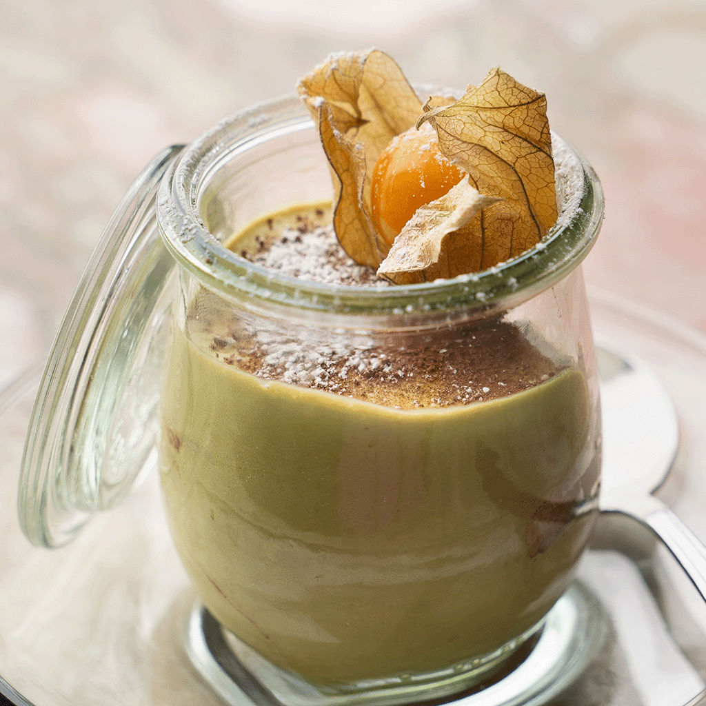 Glas mit cremigem Kürbis-Tiramisu, bestäubt mit Kakao und dekoriert mit einer Physalis (Serviervorschlag)
