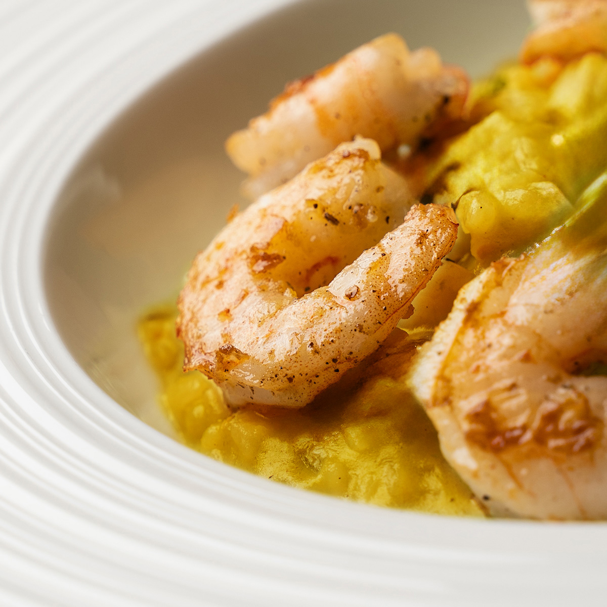 Teller mit cremigem Kürbisrisotto, belegt mit gebratenen Garnelen (Serviervorschlag)