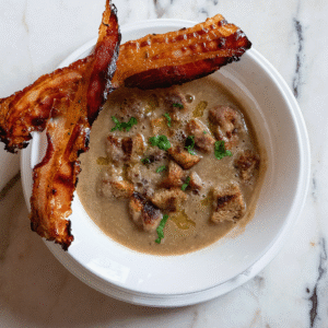 Teller mit cremiger Maronisuppe, garniert mit knusprigen Speckstreifen und Croutons (Serviervorschlag)