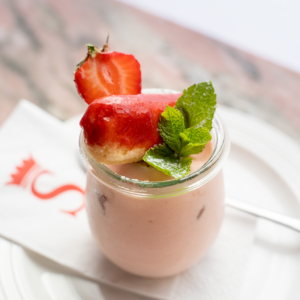 Erdbeertiramisu im Glas mit frischen Erdbeeren und Minze dekoriert, serviert auf weißem Teller im Café Savoy (Serviervorschlag)